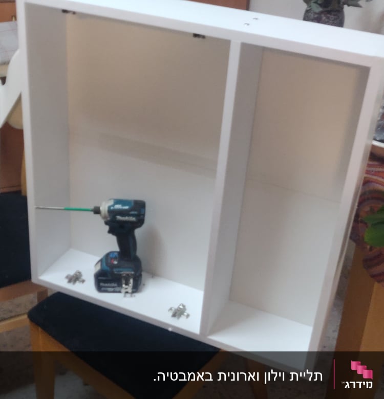 ארון לבן עם מקדחה וכלי עבודה על כיסא